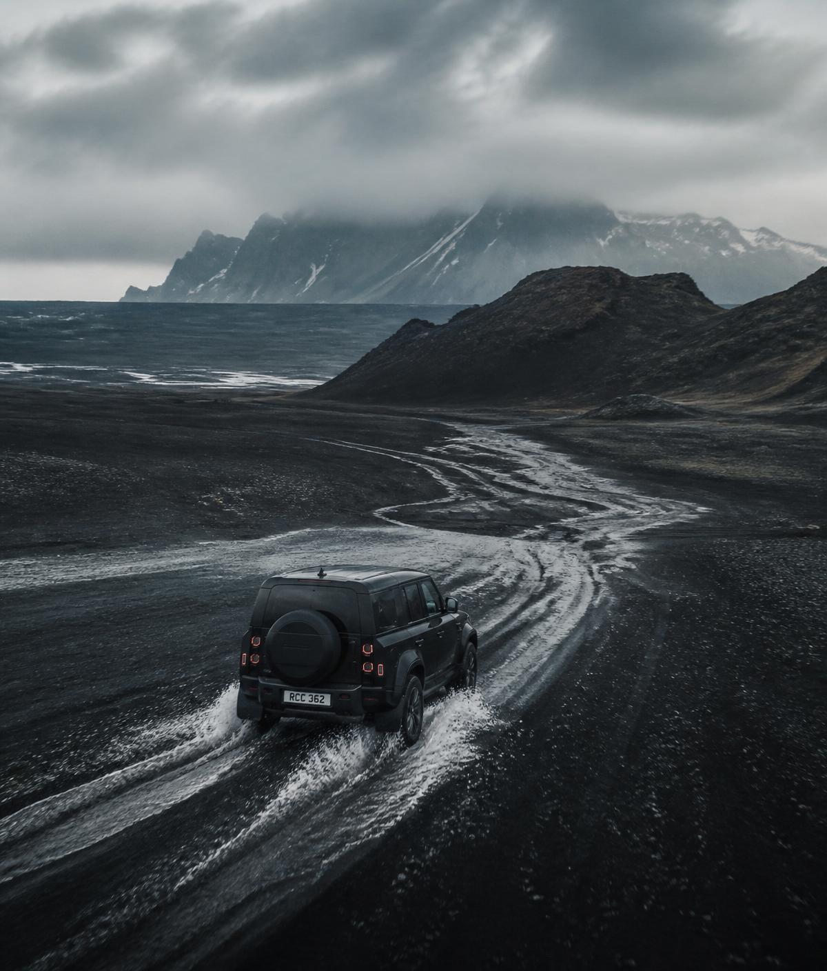 Geländewagen fährt durch eine vulkanische Schwarzsand-Landschaft